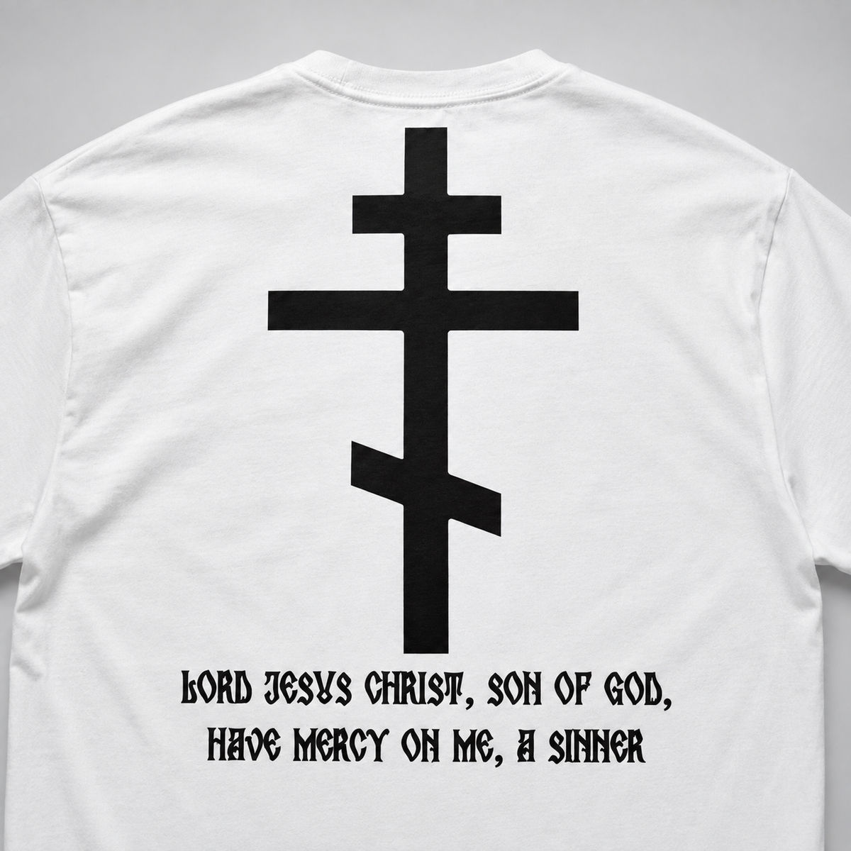 Rückansicht eines weißen Langarm-T-Shirts mit großem schwarzem orthodoxem Kreuzmotiv und gotischer Aufschrift „HERR JESUS CHRISTUS, SOHN GOTTES, ERBARME DICH MEINER, DES SÜNDERS“.