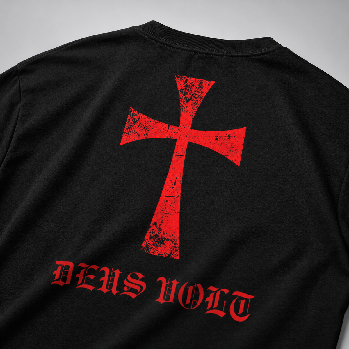 Nahaufnahme der Rückseite eines schwarzen Langarmshirts mit großem rotem Kreuzmotiv im Used-Look und roter gotischer Aufschrift „DEUS VOLT“.