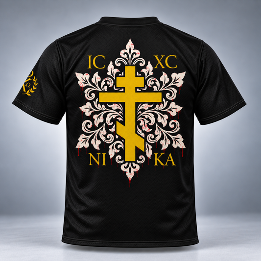Black short-sleeve athletic jersey shown from the back, featuring a large yellow and white ornamental cross graphic with gold letters and a small gold emblem on the sleeve, photographed against a gray gradient studio background.