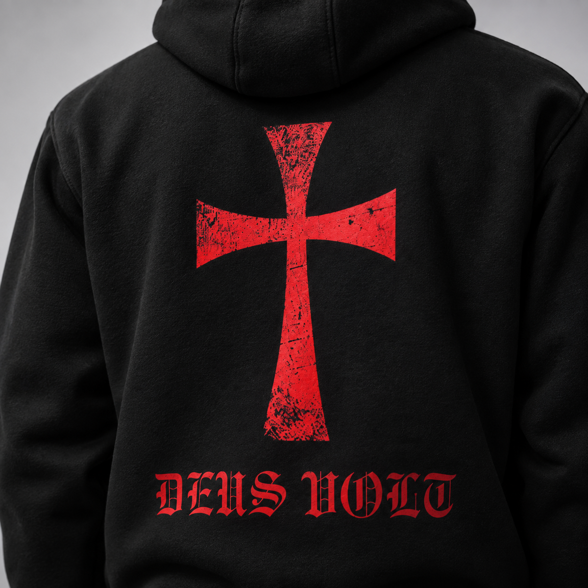 Black hoodie shown from the back, featuring a large distressed red cross graphic and the words 'DEUS VOLT' in red Gothic-style lettering below it, photographed against a neutral gray background.