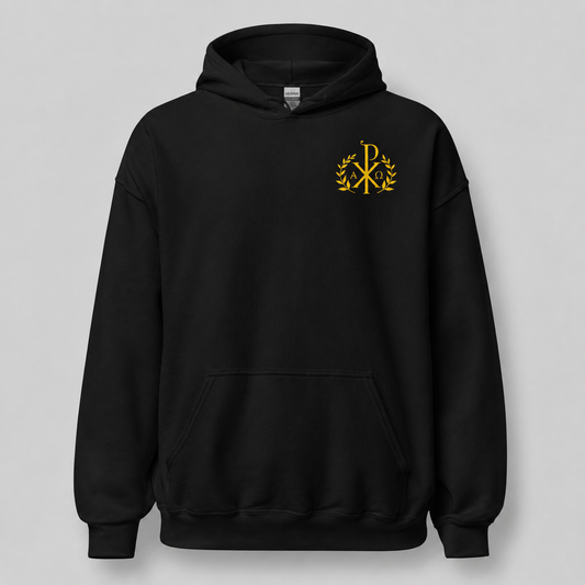 A black pullover hoodie with a small gold Chi-Rho monogram enclosed in a laurel wreath on the left chest, displayed against a neutral gray background.