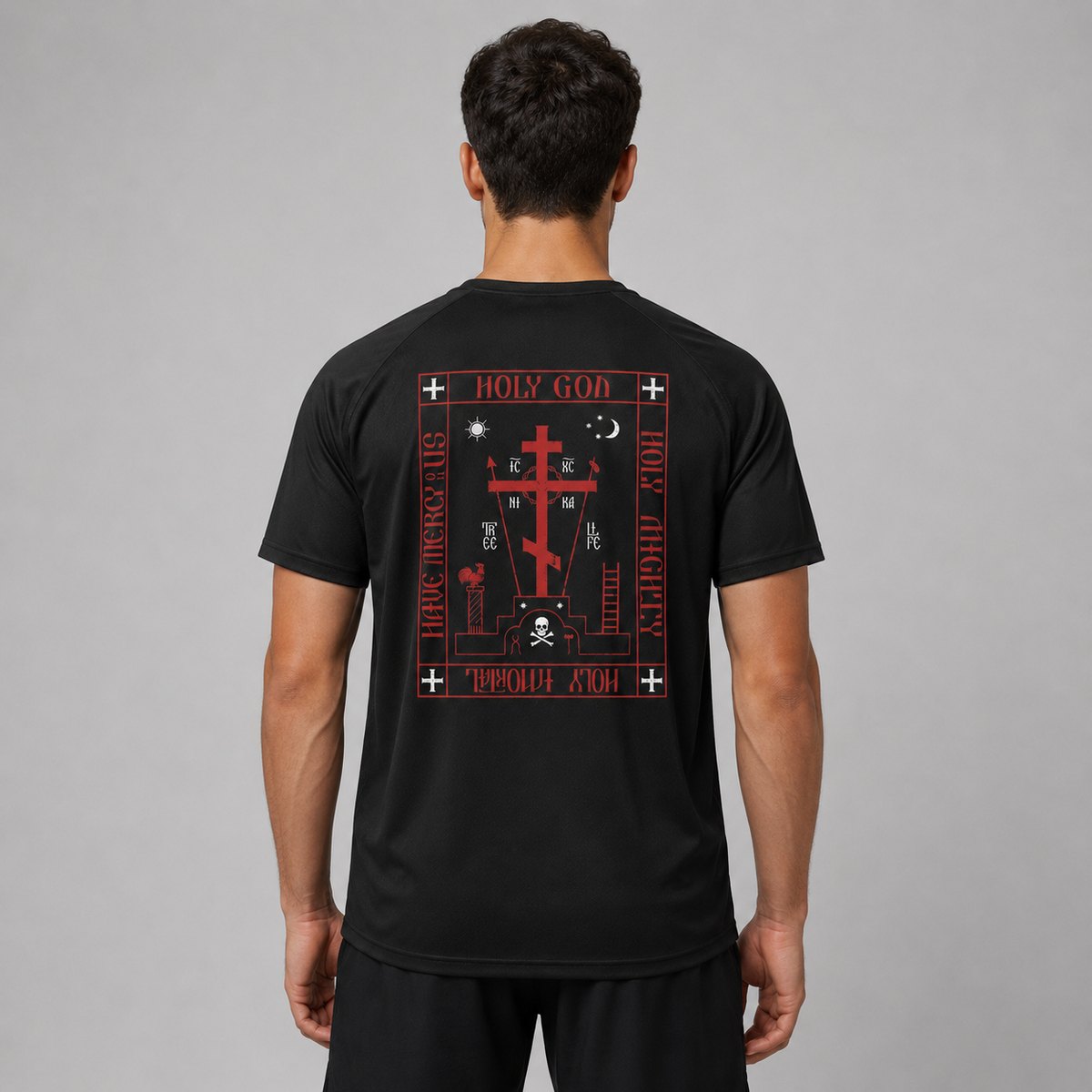 Un bărbat văzut din spate, purtând un tricou negru cu imprimeu mare gotic roșu și alb, reprezentând o cruce, un craniu și text religios.
