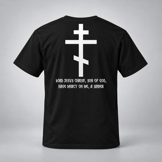 A black short-sleeve t-shirt shown from the back, featuring a large white Eastern Orthodox cross graphic and the text 'Lord Jesus Christ, Son of God, Have Mercy On Me, A Sinner' printed in white below it, set against a neutral gray background.