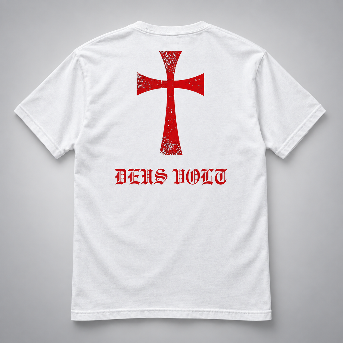 Rückansicht eines weißen kurzärmeligen T-Shirts mit großem rotem Kreuzmotiv im Used-Look und roter gotischer Aufschrift „DEUS VOLT“ darunter vor hellgrauem Hintergrund.