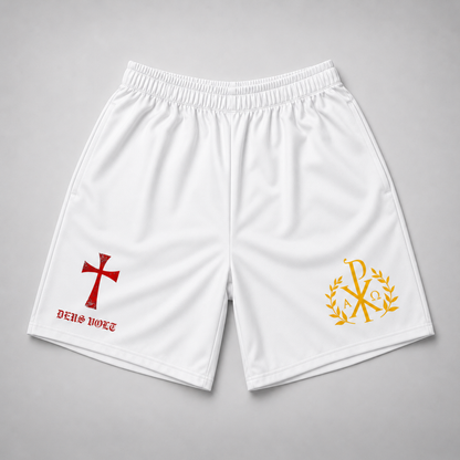 White athletic shorts with an elastic waistband, featuring a red cross and 'DEUS VULT' text on the left leg, and a gold Chi-Rho emblem with laurel leaves on the right leg, displayed flat on a gray background.