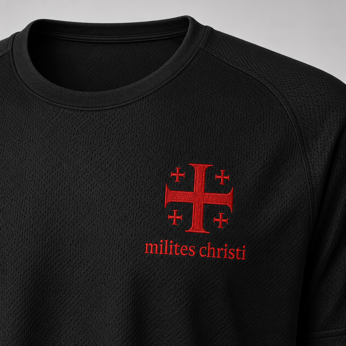 Close-up of a black textured athletic t-shirt featuring a red Templar-style cross with smaller crosses in the corners and the text 'milites christi' printed in red below it.