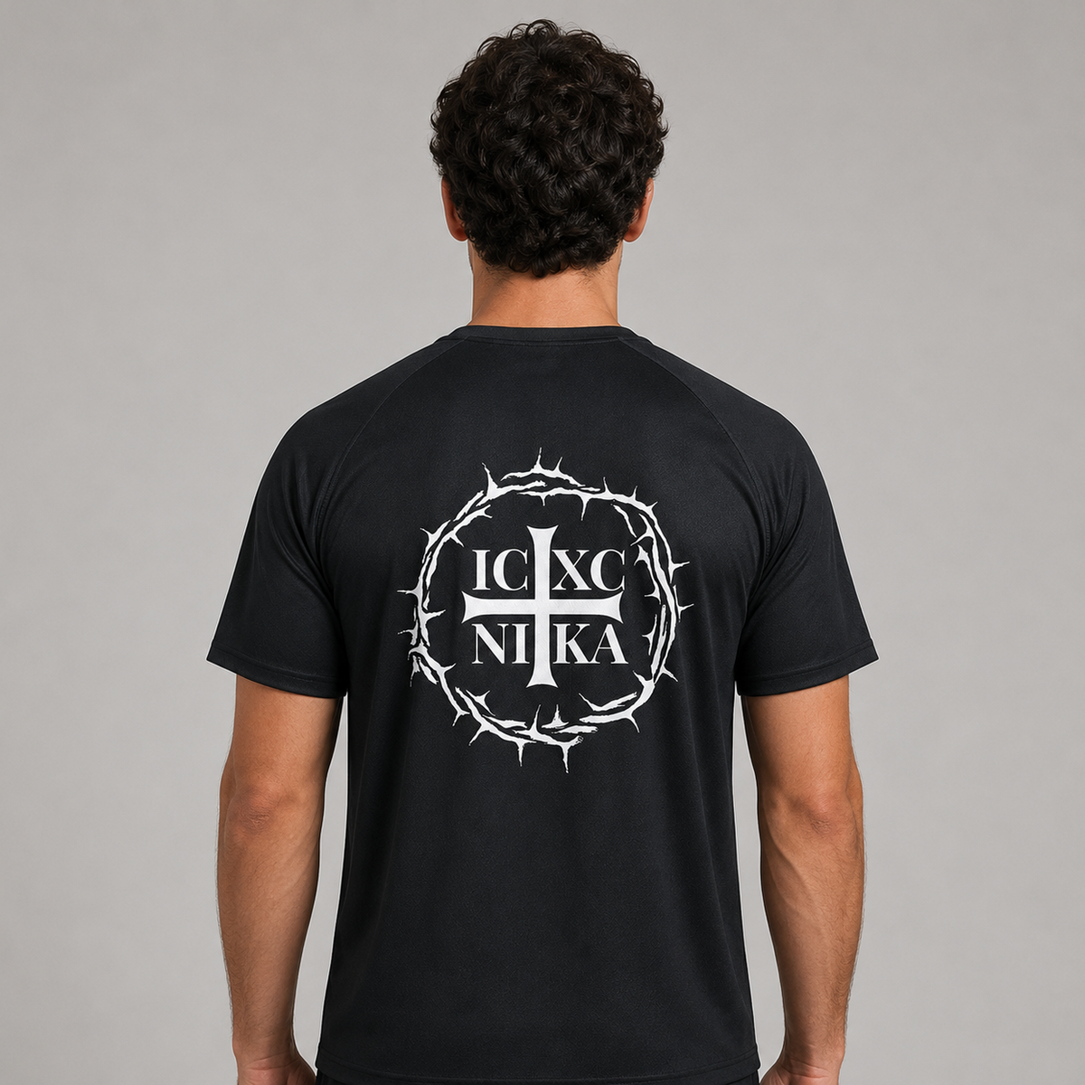 Un bărbat văzut din spate, purtând un tricou negru cu un imprimeu alb. Imprimeul reprezintă o cunună circulară de spini care înconjoară literele „IC XC NI KA” 