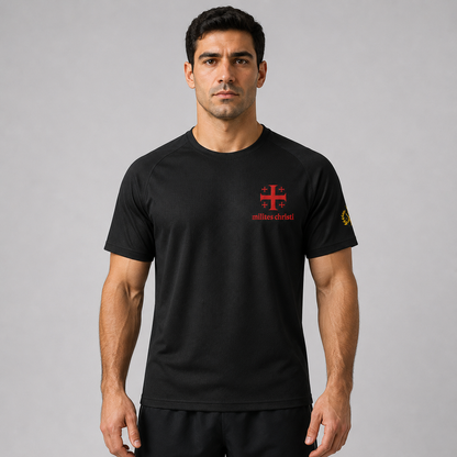 A man wearing a black short-sleeve athletic t-shirt with a red 'milites christi' cross logo on the chest and a yellow sleeve logo, photographed against a neutral gray background.