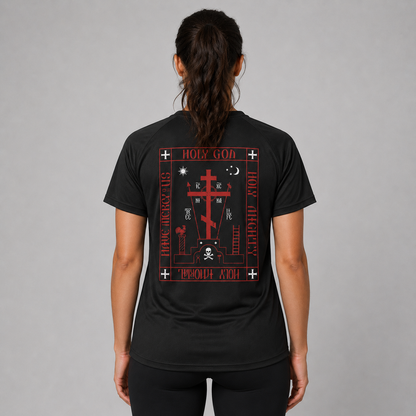 O femeie văzută din spate, purtând un tricou negru cu mâneci scurte și imprimeu mare gotic roșu și alb, împreună cu colanți negri, pe un fundal gri neutru de studio.