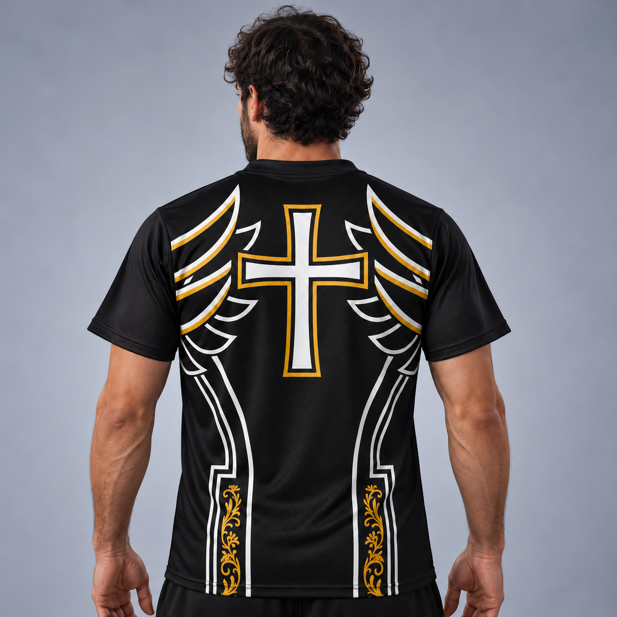 A man viewed from the back wearing a black athletic t-shirt with a large white and gold winged cross graphic on the back, set against a neutral gray studio background.