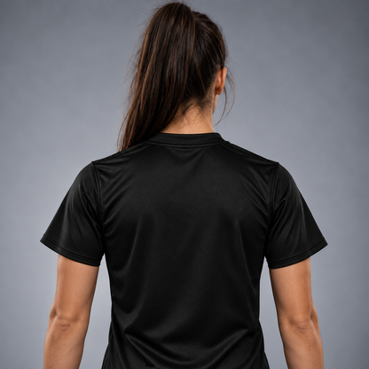 O femeie văzută din spate, purtând un tricou sport negru cu mâneci scurte, care evidențiază textura materialului pe spate, pe un fundal gri neutru de studio.