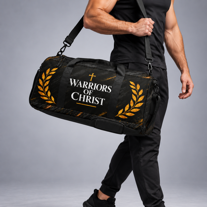 A man in a black athletic outfit carrying a black duffel bag with gold laurel designs and the text 'WARRIORS OF CHRIST' printed on the front, set against a gray studio background.