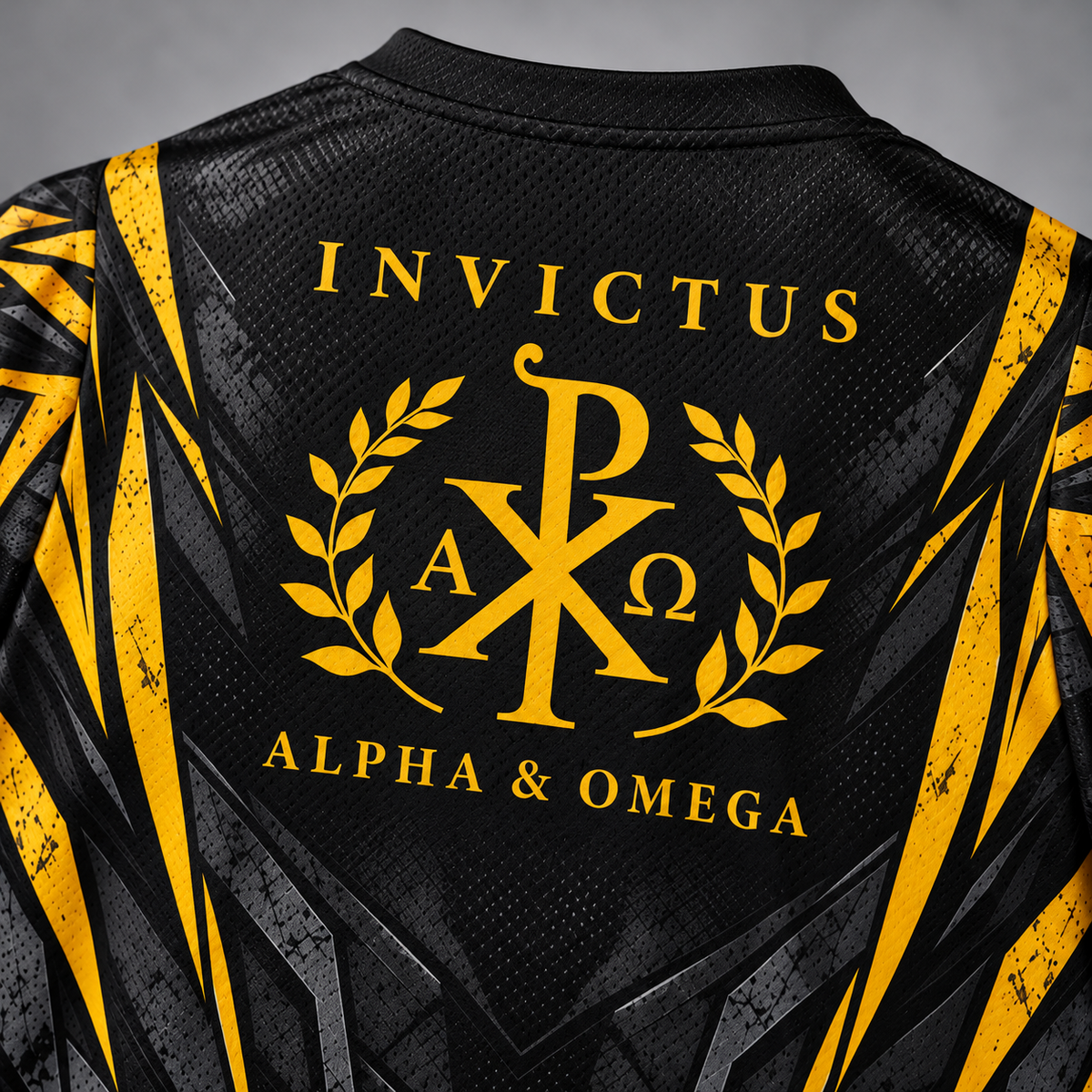 Close-up of the back of a black athletic jersey with yellow and gray geometric side panels and a large yellow Greek-letter crest reading INVICTUS ALPHA & OMEGA with laurel branches.