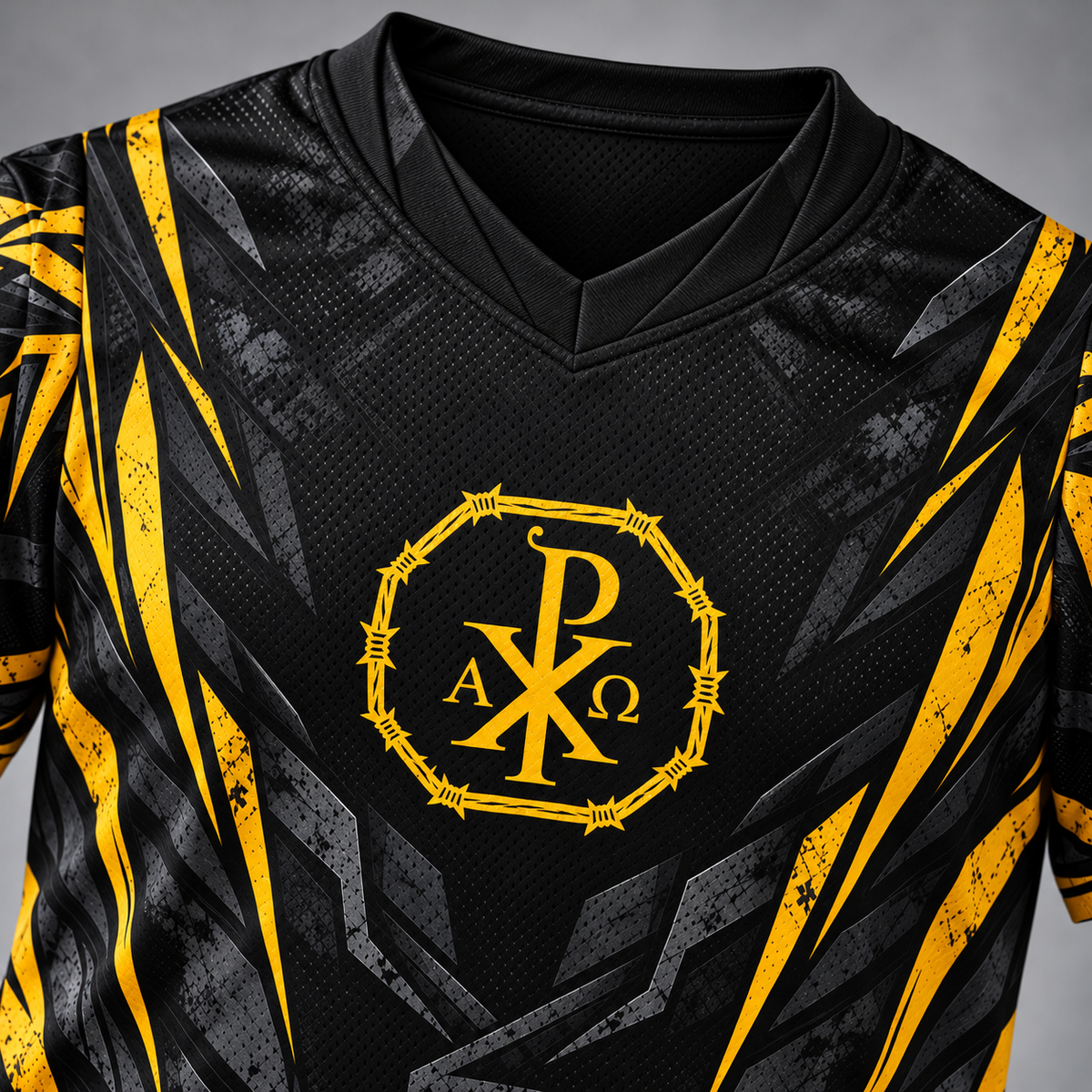 A close-up of a black athletic jersey with yellow and gray graphic patterns, featuring a yellow Chi-Rho style monogram with the letters P, A, X, and Ω on the chest.
