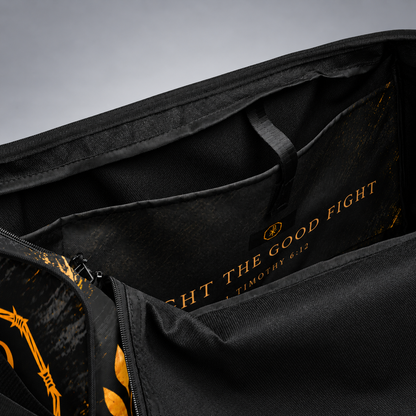 Close-up of the interior of a black bag or duffel with gold printed text reading 'FIGHT THE GOOD FIGHT' and a small circular logo, plus gold graphic accents along a zipper.