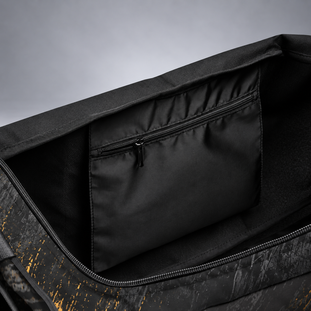 Close-up of the interior of a black duffel bag, showing a zippered compartment lining and a dark patterned exterior with subtle gold speckles.