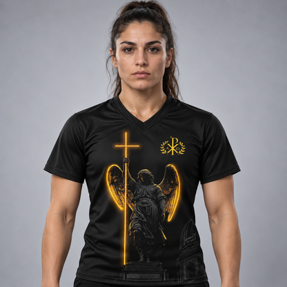 A woman modeling a black V-neck athletic jersey with a glowing golden angel graphic and a gold Chi-Rho emblem on the chest, set against a neutral gray studio background.