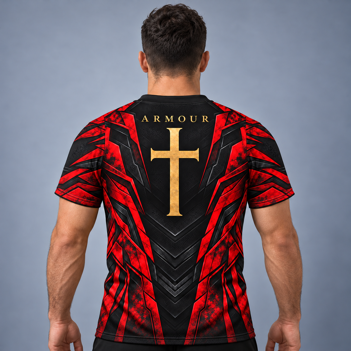 A man viewed from behind wearing a short-sleeve rugby jersey with a red and black geometric pattern and a large gold cross on the back. The word 'ARMOUR' is printed above the cross.