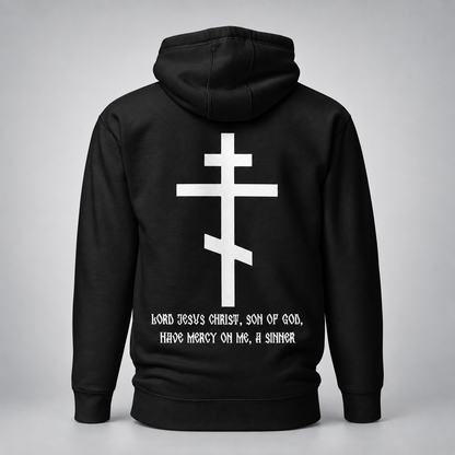 Rückansicht eines schwarzen Hoodies mit großem weißem Kreuzmotiv und weißer Aufschrift „Herr Jesus Christus, Sohn Gottes, erbarme Dich meiner, des Sünders“ vor hellgrauem Studiohintergrund.