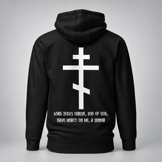 Black hoodie shown from the back with a large white cross graphic and white printed text reading, 'Lord Jesus Christ, Son of God, Have Mercy on Me, A Sinner,' on a light gray studio background.