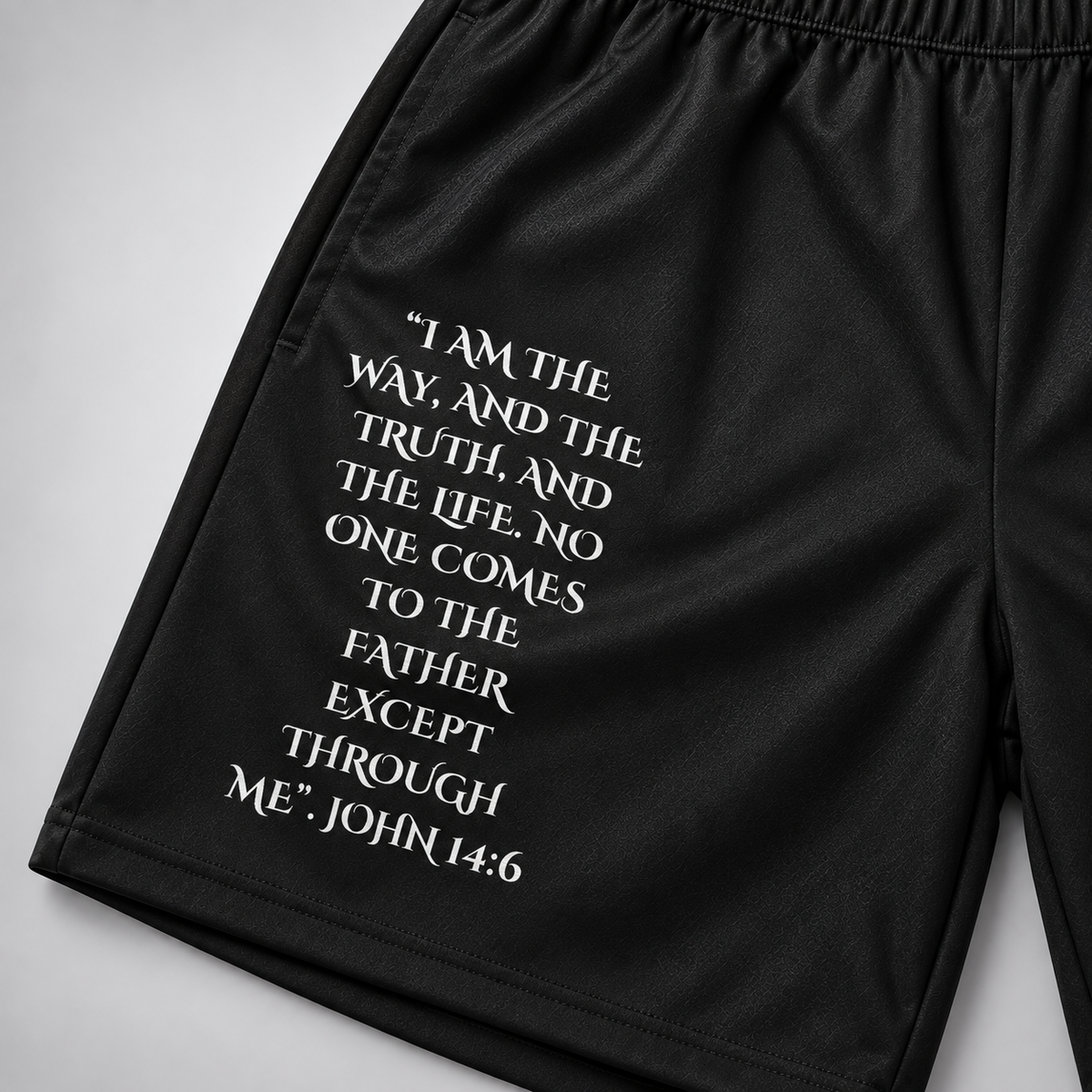 Black athletic shorts with a white biblical quote printed on the left leg 