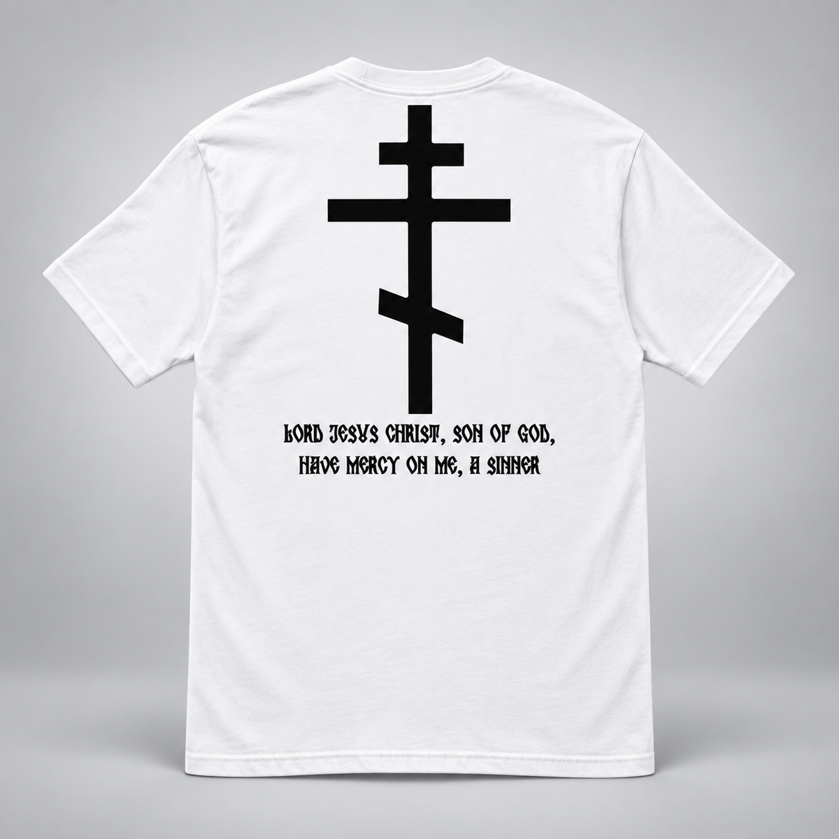Rückansicht eines weißen kurzärmeligen T-Shirts vor hellgrauem Hintergrund mit großem schwarzem orthodoxem Kreuzmotiv und schwarzer Aufschrift „HERR JESUS CHRISTUS, SOHN GOTTES, ERBARME DICH MEINER, DES SÜNDERS“.