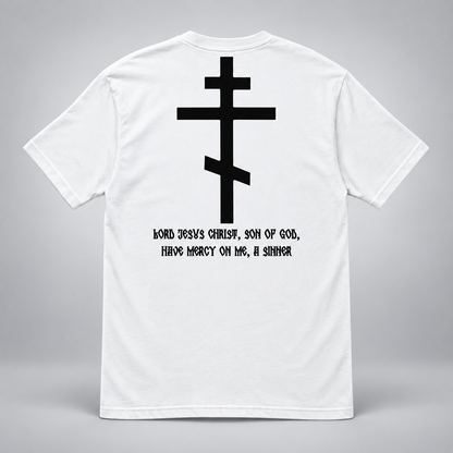 Rückansicht eines weißen kurzärmeligen T-Shirts vor hellgrauem Hintergrund mit großem schwarzem orthodoxem Kreuzmotiv und schwarzer Aufschrift „HERR JESUS CHRISTUS, SOHN GOTTES, ERBARME DICH MEINER, DES SÜNDERS“.